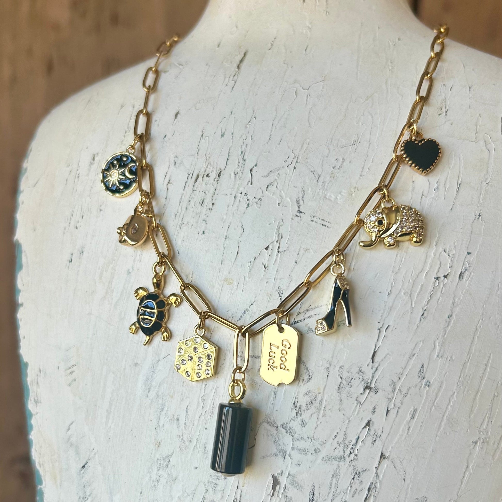 Necklace with various charms on a mannequin bust against a wooden background