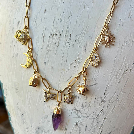 Gold necklace with purple pendant on a white mannequin bust.