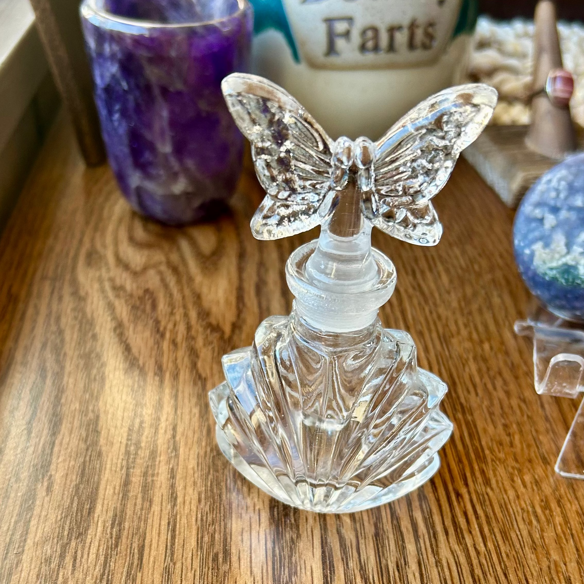 Crystal butterfly-shaped object on a wooden surface with decorative items in the background.