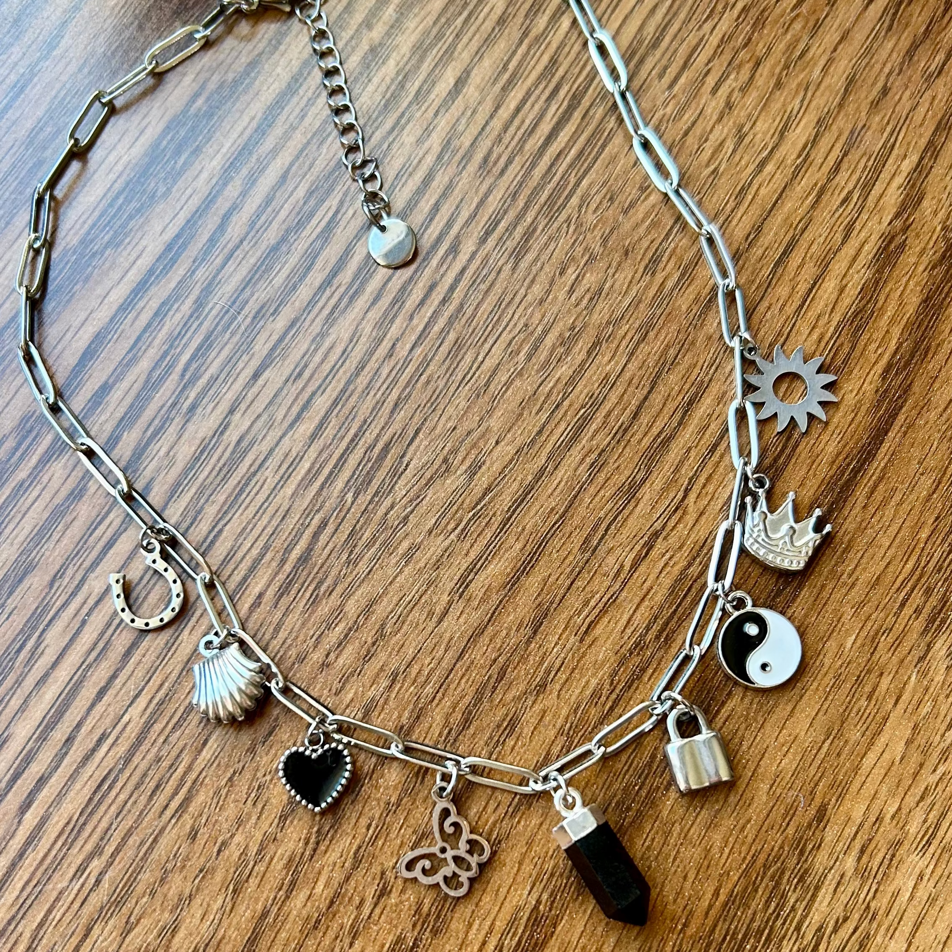 Silver necklace with various charms on a wooden surface