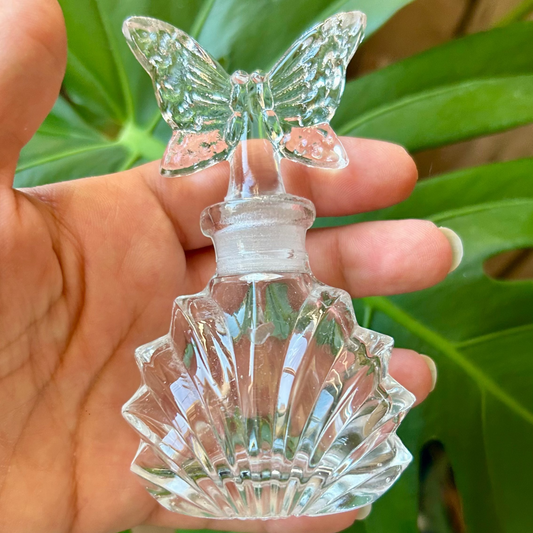 Clear glass butterfly ornament held in front of green leaves