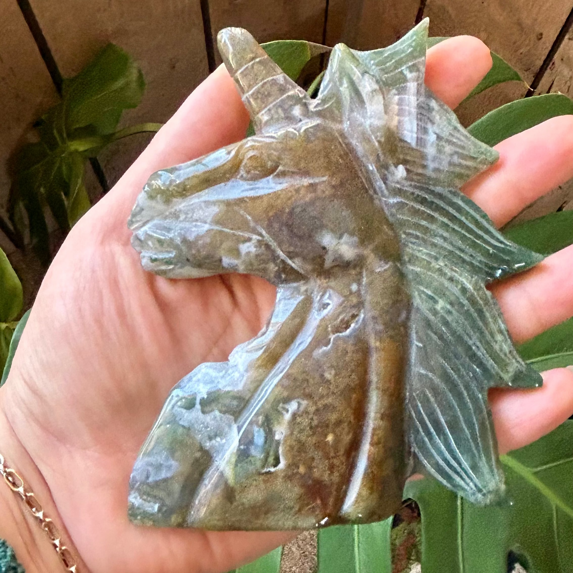 Hand holding a translucent green stone against a wooden background